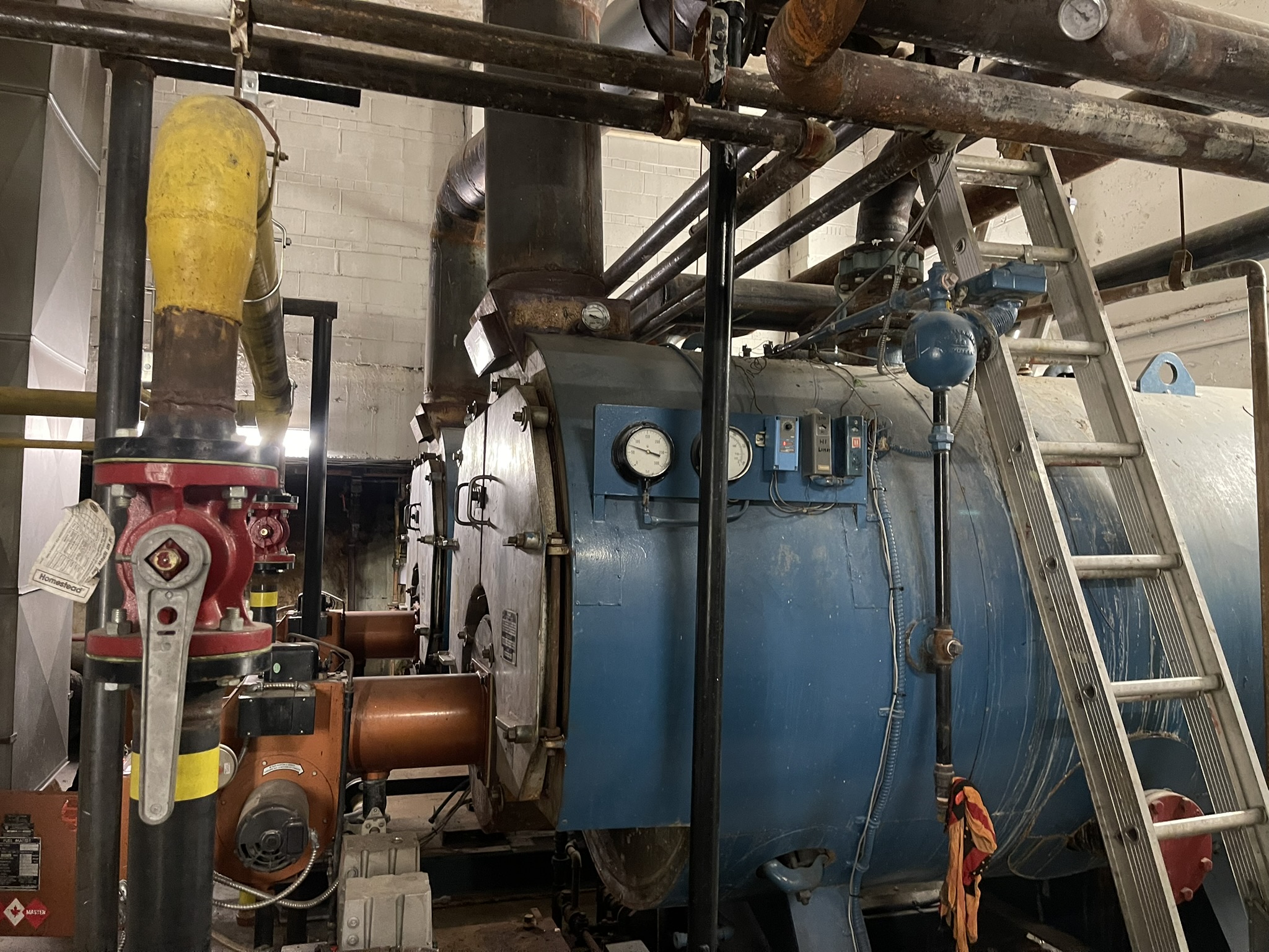 Aging fire-tube boiler with analog gauges in a commercial mechanical room